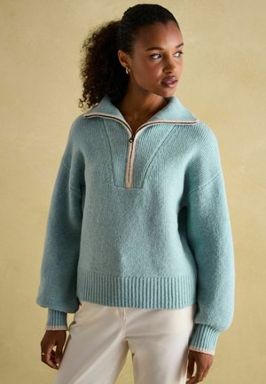 Light blue pullover sweater with a zip neck, wide ribbed cuffs, and hem. Features a textured knit and a striped accent along the collar.