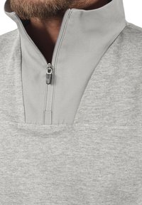 Grå fleecegenser med halv-zip krage, teksturert stoff og en liten frontlomme. Har et mykt, avslappet design med klassisk passform.
