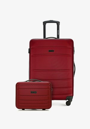 Červený pevný skořepinový kufr na kolečkách s teleskopickou rukojetí a odpovídající červená pevná skořepinová příruční taška, obě s texturovanými vodorovnými liniemi.