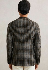 Hnedo-modrý blejzer s vzorom houndstooth, so štruktúrovaným dizajnom, prispôsobeným strihom a jedným rozparkom na chrbte. Texturovaná tkanina s viditeľným šitím.