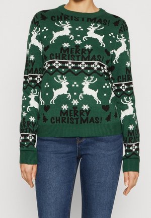 Zielony sweter świąteczny z białymi reniferami, płatkami śniegu oraz czarnym napisem „Wesołych Świąt!” noszony z niebieskimi dżinsami.
