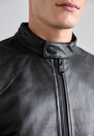 Black leather jacket featuring a high collar, zipper closure, and snap fastener. Smooth texture with subtle sheen and clean lines.