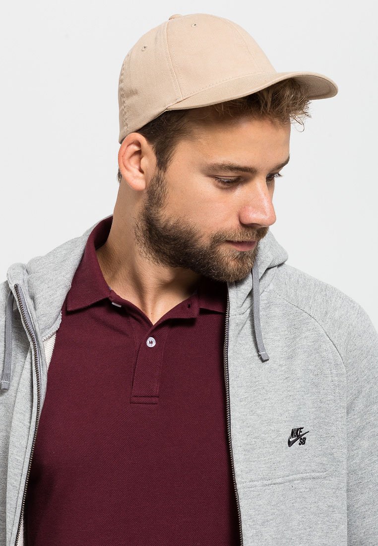 Hallgrey zip-up kapuuts, mille all on maroon polo, ning seljas on beezist baseball müts. Kapuutsil on Nike logo rinnas ja nöörid. Üksikute tekstuuridega.