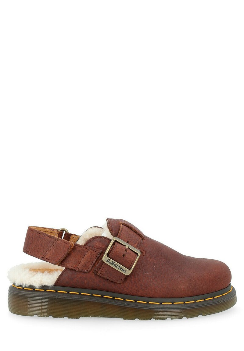 Chaussure en cuir marron avec une sangle à boucle, doublure intérieure en fourrure blanche et semelle en caoutchouc. Elle présente des coutures jaunes le long du bord de la semelle.