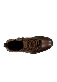 Bruine leren wandelschoen met een gevoerde kraag, ingewikkelde veters, ronde neus en gestructureerd oppervlak. Bevat een zijrits en logodetail.