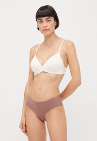 Soutien-gorge blanc sans couture avec un décolleté en V profond, associé à des culottes hipster marron lisses, les deux en tissu doux pour le confort.