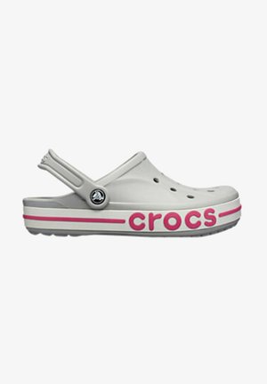 Jasnoszary chodak Crocs z paskiem na piętę, otworami wentylacyjnymi oraz różowym napisem „crocs” na grubej białej podeszwie z różowym paskiem.