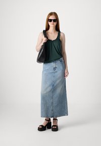 Ochelari de soare negri, bluză verde fără mâneci cu bretele volă, fustă maxi din denim albastru deschis, și sandale negre cu talpă înaltă. Ține o geantă neagră.