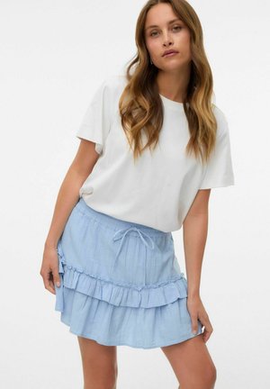 Jupe à volants superposés bleu clair avec une taille élastique et un cordon de serrage ajustable. Associée à un t-shirt blanc à manches courtes uni.
