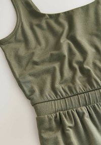 Olivegrünes ärmelloses Kleid aus weichem, dehnbarem Stoff. Verfügt über eine geraffte Taille und eine glatte Textur mit subtilen Falten.