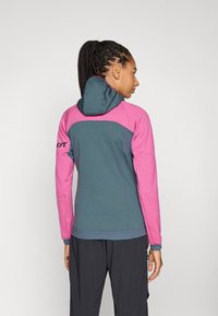 Hooded jacket featuring a color-block design with teal and pink sections, made of soft, textured fabric; snug fit and elastic cuffs.