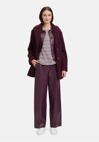 Bordeaux gekleed jasje met textuur over een gestreept shirt, gecombineerd met burgundy wijde faux leren broek en witte sneakers.