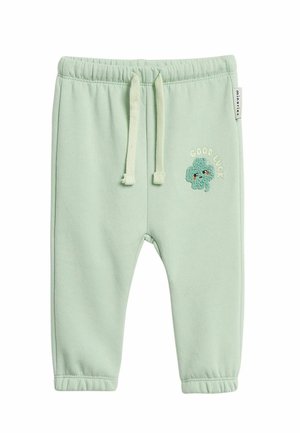 Hellgrüne Kleinkinderhose mit elastischem Bund, Kordelzug und eingesticktem "Viel Glück"-Text mit einem lachenden Kleeblatt am rechten Bein.