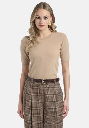 Beige, rövid ujjú kötött pulóver, környakú kivágással, barna kockás, magas derekú nadrággal és textúrált barna övvel párosítva.