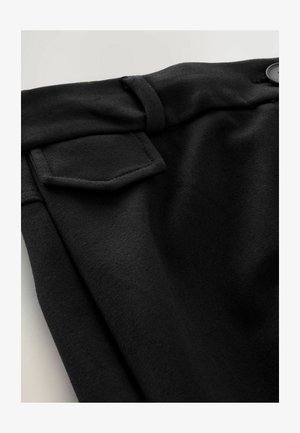 Schwarzer Stoff mit glatter Textur, einem gefalteten Taillenbund und einem kleinen aufgenähten Taschen-Detail. Enthält einen Knopfakzent.