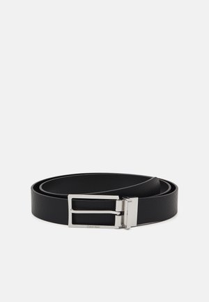 Cintura nera testurizzata realizzata in materiale sintetico con una fibbia a doppia punta in argento. Presenta un lato interno liscio e un design elegante.