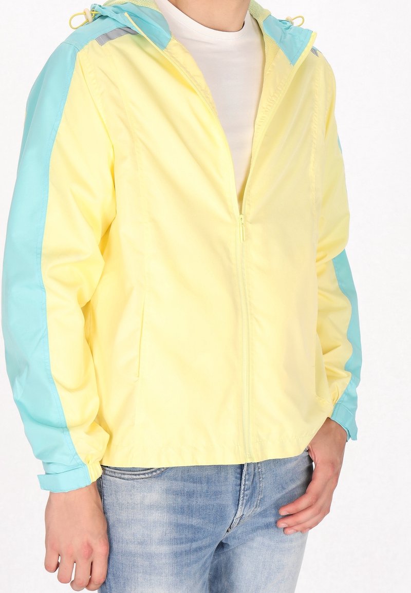 Lichtgewicht windjack met een geel middenstuk en turquoise mouwen, voorzien van een capuchon, ritssluiting en elastische boorden. Gladde nylon textuur.