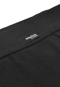 Black fabric with a textured surface, featuring a prominent label reading "spitzpub studios" in white on the top edge.