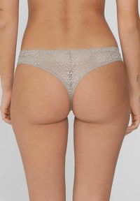 String en dentelle de couleur grise douce, avec des motifs floraux, une taille étroite et une coupe taille basse, mettant en avant le confort et l'ajustement.