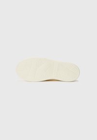 Semelle de chaussure blanche avec un motif de semelle en zigzag, texture lisse et accents en relief. Design léger avec bords arrondis et branding discret.