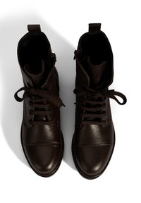 Een paar donkerbruine leren veterschoenen tot de enkels met ronde neuzen, van bovenaf bekeken op een witte achtergrond.