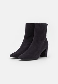 Stivali alla caviglia in suede neri con punta affusolata e tacco spesso, caratterizzati da una texture liscia e un design semplice ed elegante.