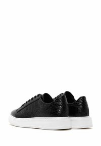 Sneaker neri con un motivo a forma di crocrodiolo, chiusura con lacci e suola in gomma bianca. Il design è a taglio basso con una finitura liscia.