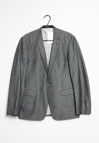 Grå blazer tillverkad av ett glatt tyg, med två framfickor, en enkel knäppning och en klassisk slagkrage. Hänger från en krok.