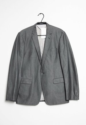 Szary marynarka z gładkiego materiału, posiadająca dwie przednie kieszenie, zapięcie na jeden guzik i klasyczny kołnierz w kształcie notcha. Wisi na wieszaku.