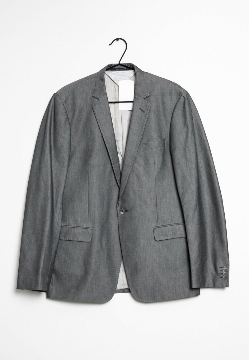 Grå blazer tillverkad av ett glatt tyg, med två framfickor, en enkel knäppning och en klassisk slagkrage. Hänger från en krok.
