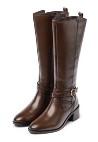 Botas de cuero marrón hasta la rodilla con una textura suave, cremallera lateral y una correa decorativa con una hebilla en tono dorado. Diseño de tacón cuadrado.