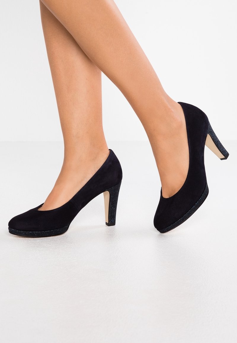 Svarta mockaskor med hög klack och rund tå, med en glittrig svart plattform och hälaccent. Slät textur och klassisk design.