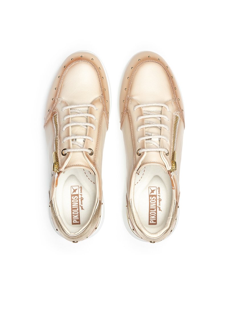 Zapatillas de cuero beige con un diseño de caña baja, que cuentan con tachuelas doradas, cordones y un cierre lateral para un fácil uso. Suela de goma para una mejor tracción.