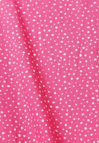 Tissu rose avec des petits pois blancs irréguliers dispersés, montrant de légers plis et une texture.