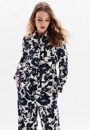 Blümchenmuster, marineblaues und cremefarbenes Stoffoutfit mit einer kragenlosen Jacke mit Knöpfen und weit geschnittenen Hosen, aus strukturiertem Leinen-Mix.