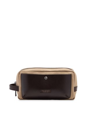 Borsa da toilette rettangolare in tessuto beige con una grande tasca frontale in pelle marrone scuro e manico laterale.