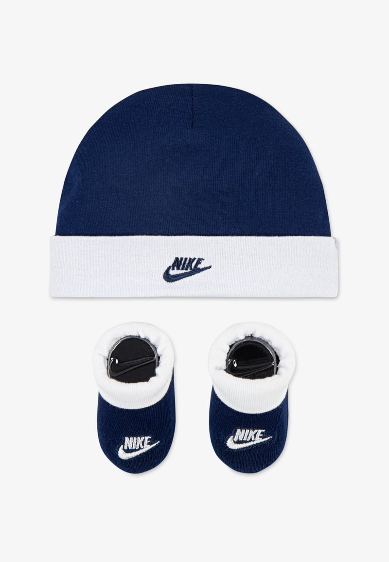 Σκούφος ναυτικού χρώματος με λευκό φιόγκο και λογότυπο Nike, συνδυασμένος με ναυτικά μποτάκια που έχουν λευκή επάνω πλευρά και branding Nike. Μαλακό βαμβακερό υλικό.