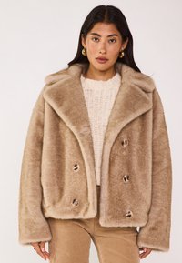 Manteau à double boutonnage en fausse fourrure beige doux, doté d'un large col, de gros boutons et d'une coupe oversize. Tissu texturé à l'apparence moelleuse.