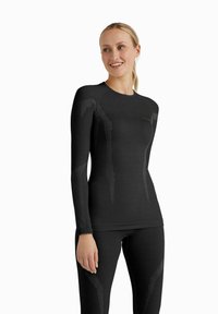 Czarna, długorękawowa koszulka sportowa oraz dopasowane legginsy z textured rib, eleganckim designem i subtelnym gradientowym wzorem pasków.