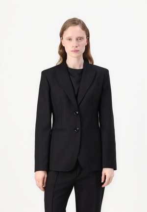 Black tailored blazer with two buttons, front pockets, and subtle seam detailing. Smooth fabric with a structured fit, complementing black trousers.