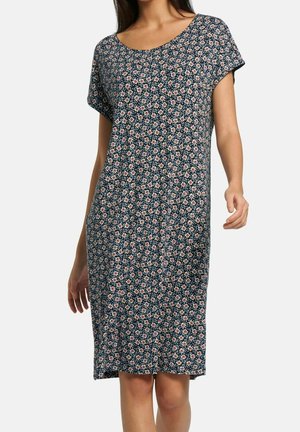 Kvinde iført knælange, kortærmede navy kjole med lille hvidt og pink blomstermønster på ensfarvet baggrund.