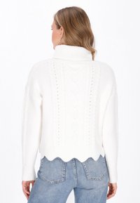 Weißer Strickpullover mit hohem Kragen, gewelltem Saum und gerippten Bündchen. Strukturiertes Muster, das vertikal entlang des Rückens verläuft.