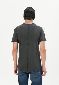 Dunkelgraues T-Shirt mit kurzen Ärmeln und abgerundetem Saum, sichtbaren Nähdetails entlang der zentralen Rückseite und einem lässigen Schnitt.