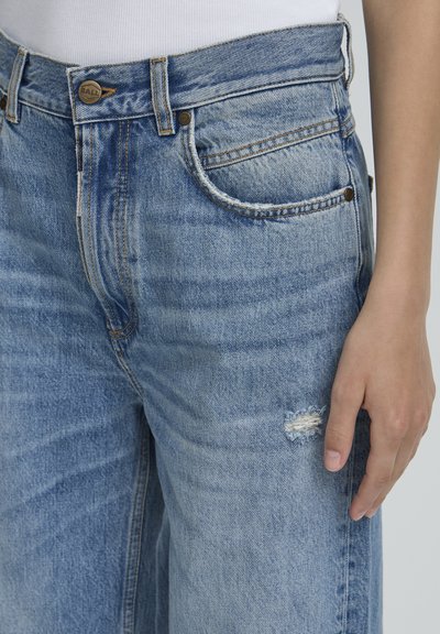 Lichtblauwe denim jeans met een relaxte pasvorm, voorzien van een versleten patch op het been, koperen hardware en een klassieke vijf-pocketontwerp.