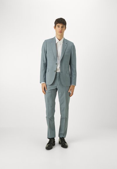 Costum bleu deschis cu rever înclinat, două butoane și pantaloni slim-fit. Purtați peste o cămașă albă pentru birou; combinați cu pantofi de birou negri.