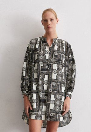 Schwarz-weißer gemusterter Hemdkleid mit langen Ärmeln, kragenlosem Ausschnitt, geometrischem Design und entspanntem Schnitt, ausgestattet mit einem asymmetrischen Saum.