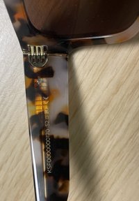 Sluneční brýle s želvovinovým vzorem a lesklým povrchem. Zlatozlaté detaily na panty. Texturované nožičky zobrazují číslo modelu a specifikace.