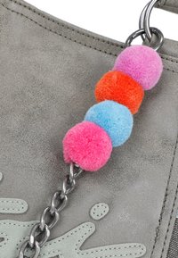 Sac en daim gris avec une poignée en chaîne et quatre pompons colorés en rose, orange et bleu en accents.