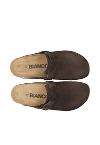 Een paar bruine suède instappers met verstelbare zijklips en tan gekussende inlegzolen met het label "BIANCO", maat 42.