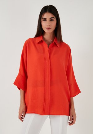 Red linen shirt with a pointed collar, button front, and wide sleeves. The fabric has a smooth texture and subtle sheen.